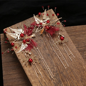 Détail de pinces à cheveux et clips d'oreilles avec pétales rouges et longs glands dorés