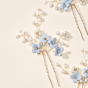 Close-up of blue floral hair pins with white pearls and rhinestones on gold wire