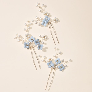 Detail of three blue floral bridal hair pins with pearls and gold U-shaped metal clips