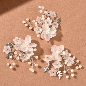 Dettaglio di tre fermagli floreali con petali rosa opachi e perle artificiali