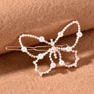 Élégante pince à cheveux papillon dorée ornée de perles blanches sur fond texturé