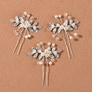 Close-up of three pearl and crystal hair pins with silver leaves for bridal styling