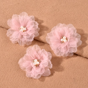 Detail of three light pink pleated mesh flower clips with pearls and gold rhinestones