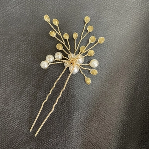 Detailed macro view of handmade gold bridal hair pin with white pearls and gold charms