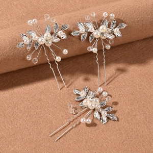 Detailed view of silver bridal hair pins with white pearls and crystals on velvet