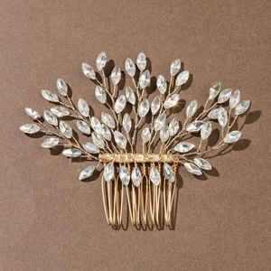 Détail d'un peigne à cheveux de mariée doré avec strass marquise en forme de feuille