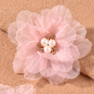 Close-up of pink chiffon layered flower hair clip with pearl and rhinestone center detail