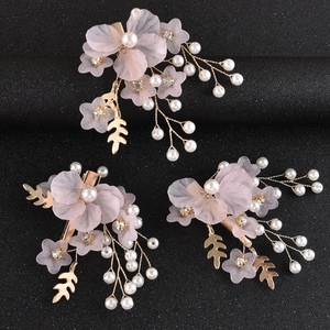 Dettaglio di tre fermagli per capelli con fiori in resina rosa, perle e foglie d'oro