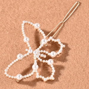 Barrette papillon dorée élégante avec perles blanches sur un fond velouté