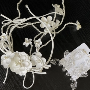 Elegant white floral bridal headpiece with pearls and acrylic butterfly clips on dark wood