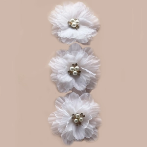 Detail of white pleated chiffon flower clips with artificial pearls and rhinestone centers