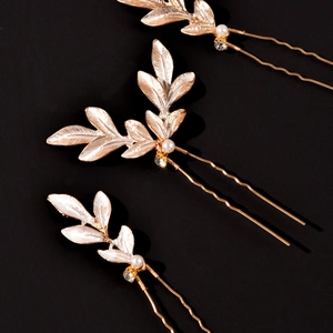 Vue détaillée de trois épingles à cheveux feuilles dorées avec perles et strass sur noir