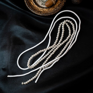 Elegant French white bow and pearl bridal headband set displayed on black silk fabric