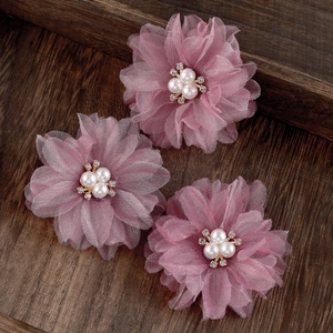 Close-up of white pleated fabric flower hair clips with pearls and rhinestones details