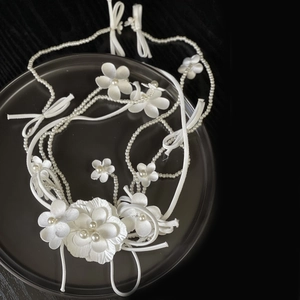 Elegant white satin flower headpiece with pearls and bow for bridal hair styling