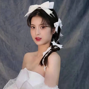 Detail of white satin bow and cascading pearls woven into a bridal braid hairstyle