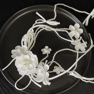 Detail of white satin flower headpiece with pearls and fabric petals for bridal hair