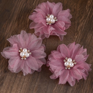 Detailed macro view of set of three handmade pleated chiffon flower hair clips with pearls