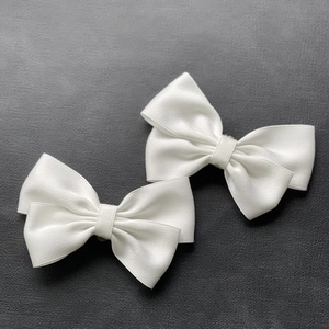 Detailed view of dual-layer white satin bow shoe clips with elegant silk finish