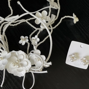 Detail view of handmade white satin flower headband with pearl tassels and matching earrings