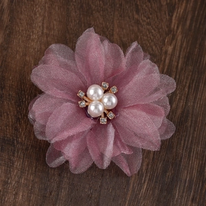 Close-up of pink layered mesh flower clip with white pearls and rhinestones on wood
