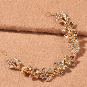 Détail d'une chaîne de cheveux de mariée dorée avec fleurs en cristal et motifs de feuilles