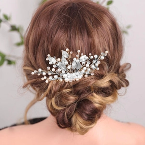 Detail of bridal hair comb with silver metal leaves and pearls in an elegant updo