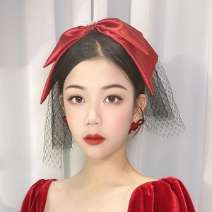 Elegant bridal headpiece with burgundy satin bow, black mesh veil, and pearl detail
