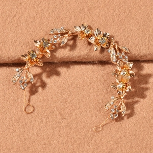 Détail de la vigne de cheveux de mariée dorée faite main avec fleurs et strass brillants