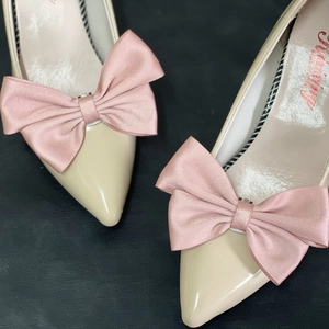 Detailed macro view of cream patent leather pointed toe shoes with silk pink bow decoration