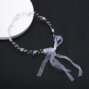 Détail de l'accessoire de mariée avec fleurs blanches et fil d'argent sur fond sombre