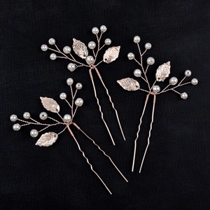 Detail view of three handmade golden leaf hair pins with pearls on black background