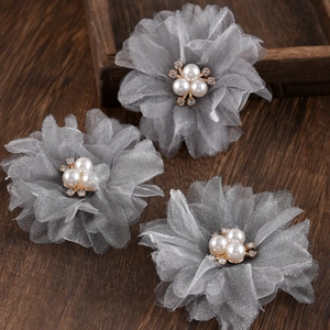 Detailed macro of three grey tulle flower clips with pearls and rhinestones on wood