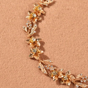 Gros plan détaillé d'une vigne à cheveux dorée pour mariée avec fleurs et strass brillants
