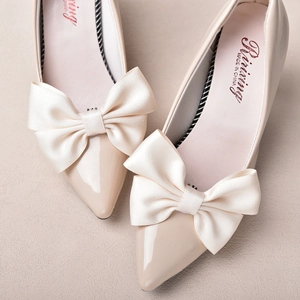 Elegant bridal beige pointed-toe heels with large satin bow accents for wedding decoration
