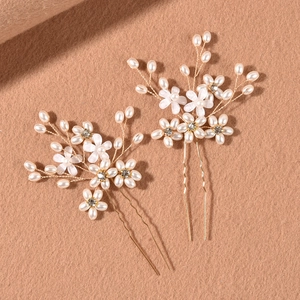 Detalle de horquillas de flores blancas hechas a mano con perlas y alambre dorado para novias