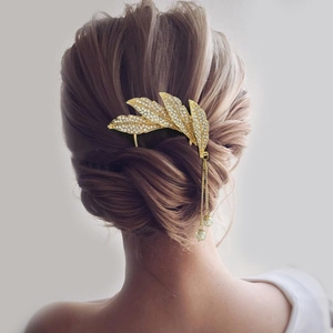Detail of a golden leaf hair fork with sparkling rhinestones and long pearl tassels