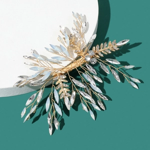 Détail d'une pince à cheveux de mariée avec feuilles dorées et strass marquise