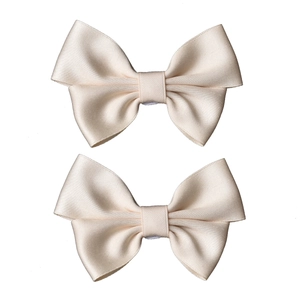 Detail of two champagne satin bow shoe clips with elegant silk texture and fine stitching