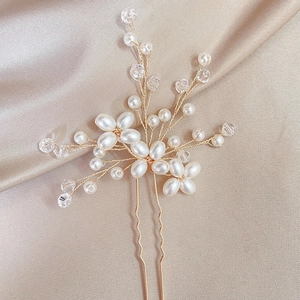 Détail d'une épingle à cheveux de mariée avec cristal rose et perles sur satin champagne