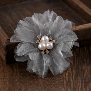 Macro detail of three grey mesh flower clips with pearls and rhinestones on wood