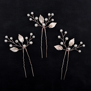 Detail of rose gold wire-wrapped leaf hair pin set with elegant white pearls and metal foliage