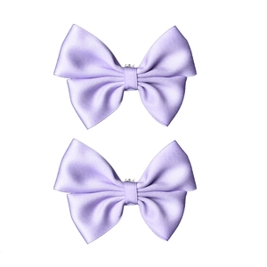 Close-up of two elegant lavender satin silk bow shoe clips with smooth glossy texture
