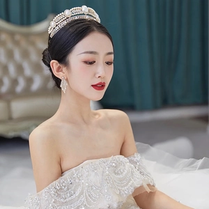 Elegant silver bridal crown and pearl rhinestone earrings set on a bride with lace gown