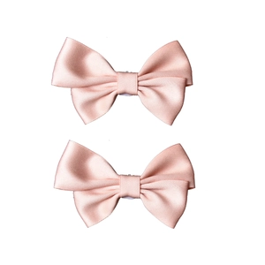 Detailed view of pink satin double-layered bow clips with a smooth silky texture