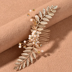 Détail d'un peigne à cheveux de mariée doré avec feuilles, perles et strass