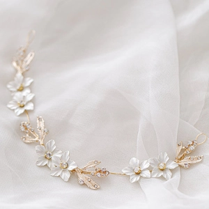 Détail d'une vigne de cheveux de mariée avec fleurs blanches et feuilles d'or sur tulle