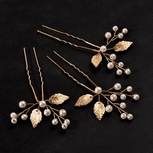 Detailed close-up of three golden leaf hairpins with white pearls on a black background