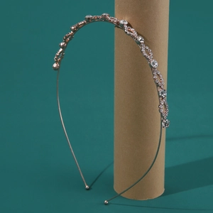 Macro shot of rose gold bridal headband with crystal rhinestones on a dark green background