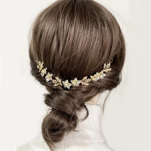 Chaîne de cheveux de mariée dorée avec fleurs blanches sur un chignon bas élégant